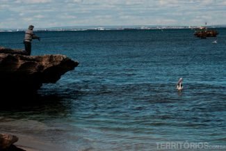 Pescador e pelicano de olho no peixe Pescador e pelicano de olho no peixe