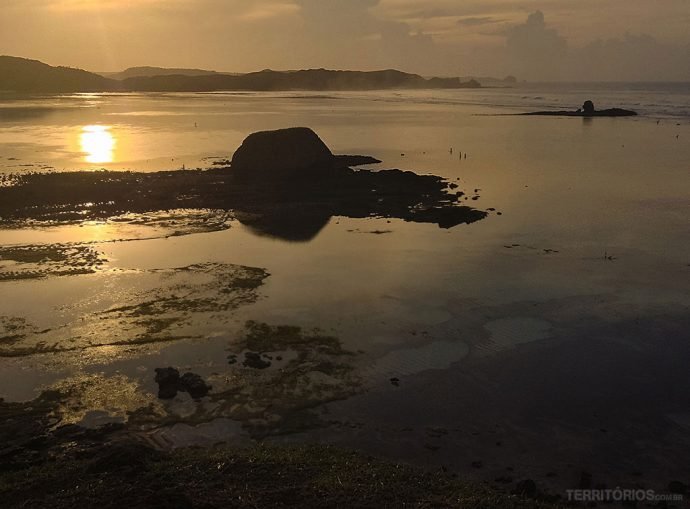 Nascer do sol nublado com pescadores aproveitando a maré baixa